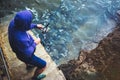 Young man holds a fishing rod and catches fish in the nature on a sea background, hipster fisherman spends vacation on the blue oc Royalty Free Stock Photo