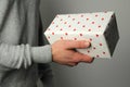 Young man holds in his hand a gift in a box on a gray background, holiday concept Royalty Free Stock Photo