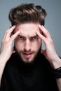 A young man holds his head and shows different human emotions: hatred, fear, despair, horror, malaise, headache, clairvoyance.