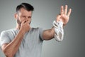 A young man holds his smelly socks and covers his nose with his hand. Nasty smell. Stink legs, fungus on the legs Royalty Free Stock Photo