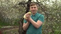 A young man holds a real duckling in his arms. A man in the garden with a bird. Royalty Free Stock Photo