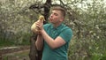 A young man holds a real duckling in his arms. A man in the garden with a bird. Royalty Free Stock Photo