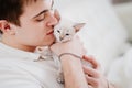 a young man holds a small white kitten and petting him. nevsky masquerade cat. Royalty Free Stock Photo