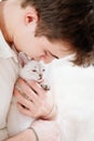 a young man holds a small white kitten and petting him. nevsky masquerade cat. Royalty Free Stock Photo