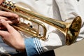 A young man holds a trumpet musical instrument.