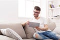 Young man at home reading on tablet