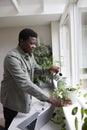 Young Man At Home Watering Plants In Office Royalty Free Stock Photo