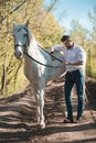 Young man with horse. Autumn outdoors scene Royalty Free Stock Photo