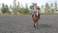 Young man horseback riding outdoor. Male jockey at horse walking at manege at farm on dark cloudy day. Beautiful nature Royalty Free Stock Photo