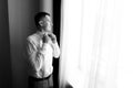 A young man husband is going to a wedding ceremony in a luxury hotel wearing a blue suit and adjusting his bow tie while waiting Royalty Free Stock Photo