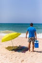 Young man with ice bar cooler under solar umbrella on a beach ne Royalty Free Stock Photo