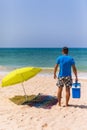 Young man with ice bar cooler under solar umbrella on a beach ne Royalty Free Stock Photo