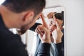 A young man indoors looking in the mirror, squeezing a pimple. Royalty Free Stock Photo