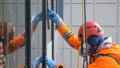 Industrial climber in bright suit and helmet washes windows at a height close up Royalty Free Stock Photo