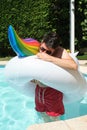 Young man inflates big unicorn inflatable ring at a swimming pool Royalty Free Stock Photo