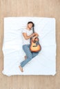 Bedtime. Guy sleeping on bed top view hugging guitar peaceful Royalty Free Stock Photo