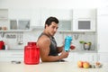 Young man with ingredients for protein shake in kitchen