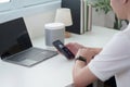Smart Technology. A man using smartphone with smart speaker on desk. Royalty Free Stock Photo