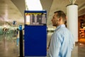 A young man at an international airport looks at a flight information board, checks his flight Royalty Free Stock Photo