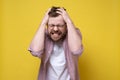 Young man is irritated, he is tearing the hair on his head in stress and showing teeth. Concept of mental health. Yellow Royalty Free Stock Photo