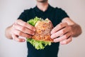 Young man isolated over background. Cut view of guy holding bun with green lettuce. Tasty delicious sandwich. Ready to Royalty Free Stock Photo