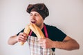 Young man over background. Guy in cook uniform biting two pieces of french baguette and enoy it. Eating fresh