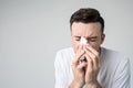 Young man isolated over background. Portrait of guy sneezing into white napkin. Sickness and coronavirus danger. Ill guy