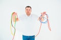 Young man isolated over white background. Confused guy hold colorful electrical cords. Good for reusing and recycling