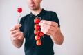 Young man isolated over white background. Cut view of guy holding cherry tomatoes in one hand and one on fork. Delicious Royalty Free Stock Photo
