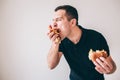 Young man isolated over white background. Glutton guy divour french fries which is held in hand. Bitten burger in Royalty Free Stock Photo