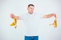 Young man isolated over white background. Mean unhappy guy hold banana`s skin in hands. Want to throw it away. Organic