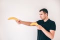 Young man isolated over white background. Side view of guy having two yellow ripe bananas and hold them as gun. Serious Royalty Free Stock Photo