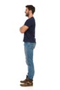 Young Man In Jeans And Blue T-shirt Is Standing With Arms Crossed And Looking Away. Side View Royalty Free Stock Photo