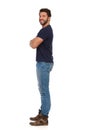 Young Man In Jeans And Blue T-shirt Is Standing With Arms Crossed. Side View Royalty Free Stock Photo