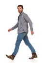 Young Man In Jeans, Boots And Lumberjack Shirt Is Walking And Talking. Side View Royalty Free Stock Photo