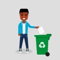 Young man in jeans and sweatshirt throwing paper in recycle bin.