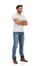 Young Man In Jeans And White T-shirt Is Standing With Arms Crossed And Looking Away Royalty Free Stock Photo