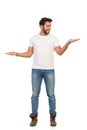 Young Man In Jeans And White T-shirt Is Standing And Compare Something