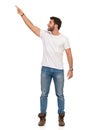 Young Man In Jeans And White T-shirt Is Standing, Smiling And Pointing Up. Front View Royalty Free Stock Photo