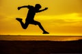 young man jump over the sun and through on the gap of hill silhouette evening colorful sky. Royalty Free Stock Photo