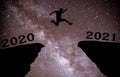 A young man jump between 2020 and 2021 years over night sky with stars and through on the gap of hill silhouette evening colorful Royalty Free Stock Photo