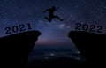 A young man jump between 2021 and 2022 years over night sky with stars and through on the gap of hill  silhouette evening colorful Royalty Free Stock Photo