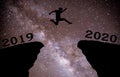 A young man jump between 2019 and 2020 years over night sky with stars and through on the gap of hill silhouette evening colorful Royalty Free Stock Photo