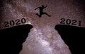 A young man jump between 2020 and 2021 years over night sky with stars and through on the gap of hill  silhouette evening colorful Royalty Free Stock Photo