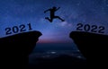 A young man jump between 2021 and 2022 years over night sky with stars and through on the gap of hill  silhouette evening colorful Royalty Free Stock Photo