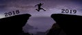 A young man jump between 2018 and 2019 years over night sky with stars and through on the gap of hill silhouette evening colorful Royalty Free Stock Photo