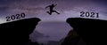 A young man jump between 2020 and 2021 years over night sky with stars and through on the gap of hill silhouette evening colorful Royalty Free Stock Photo