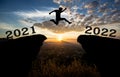 A young man jump between 2021 and 2022 years over the sun and through on the gap of hill  silhouette evening colorful sky. happy n Royalty Free Stock Photo
