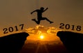 A young man jump between 2017 and 2018 years over the sun and through on the gap of hill silhouette evening colorful sky.