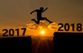 A young man jump between 2017 and 2018 years over the sun and through on the gap of hill silhouette evening colorful sky.